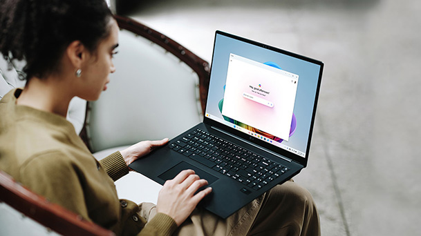 This image shows a person using a laptop, showcasing its screen displaying a colorful interface, with a message about extended battery life.