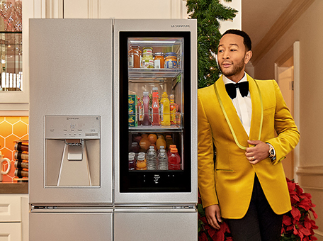 Singer John Legend leaning on an LG SIGNATURE Refrigerator.