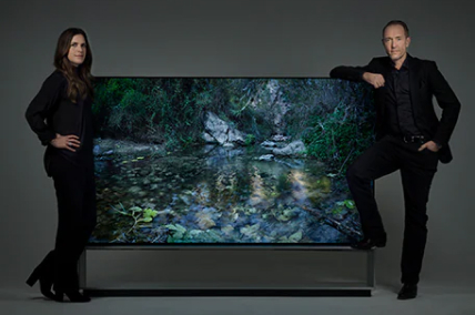 Artist duo Alexandrov Klum leaning on a LG SIGNATURE 88 TV