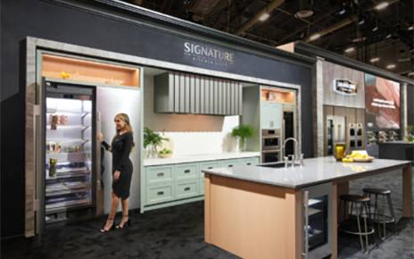 A photo of a woman standing by the refrigerator in the Signature Kitchen Suite zone at KBIS 2024