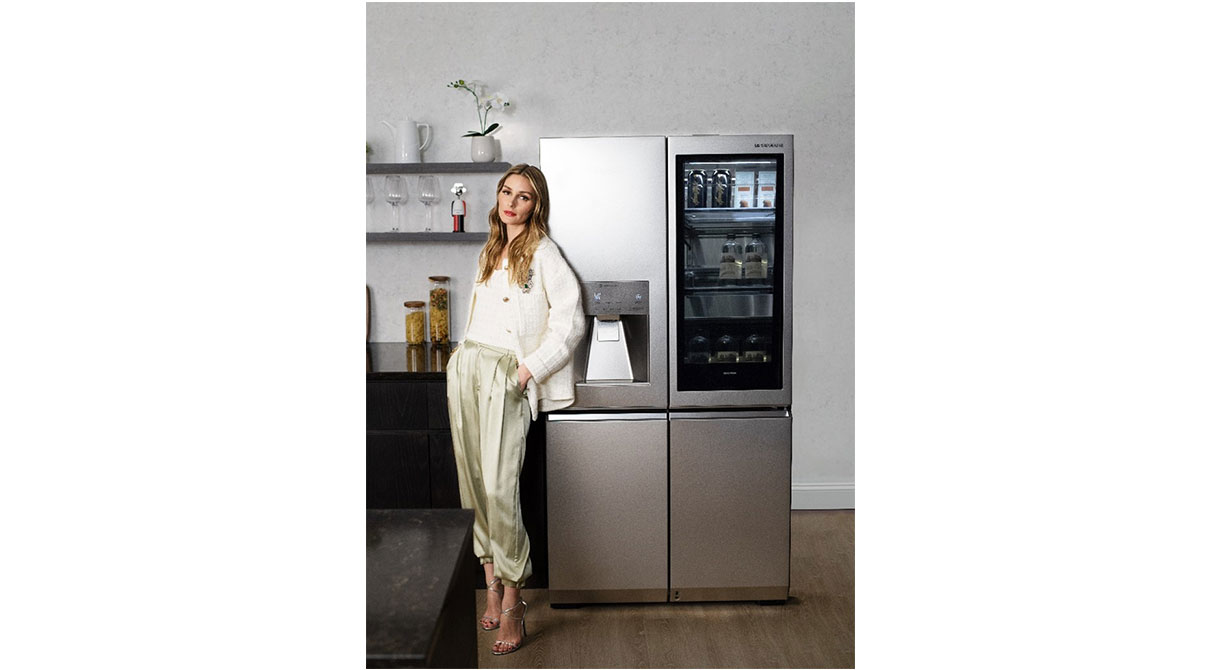 Olivia Palermo is posing in front of the LG SIGNATURE InstaView™ Door-in-Door® Refrigerator.
