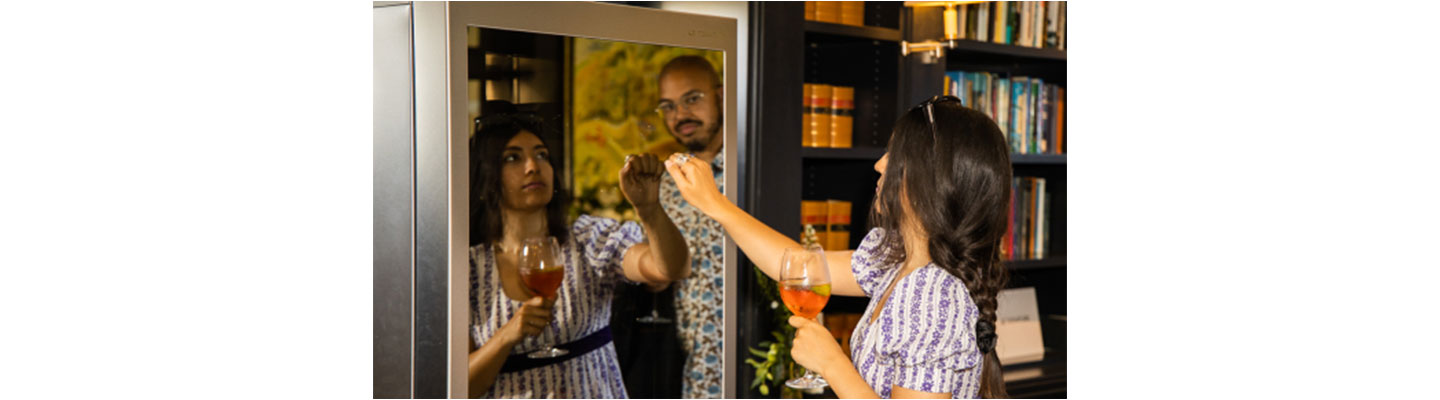 Two attendees to the LG SIGNATURE Goodwood races event check out the LG SIGNATURE Wine Cellar while testing its InstaView feature by knocking on its glass panel