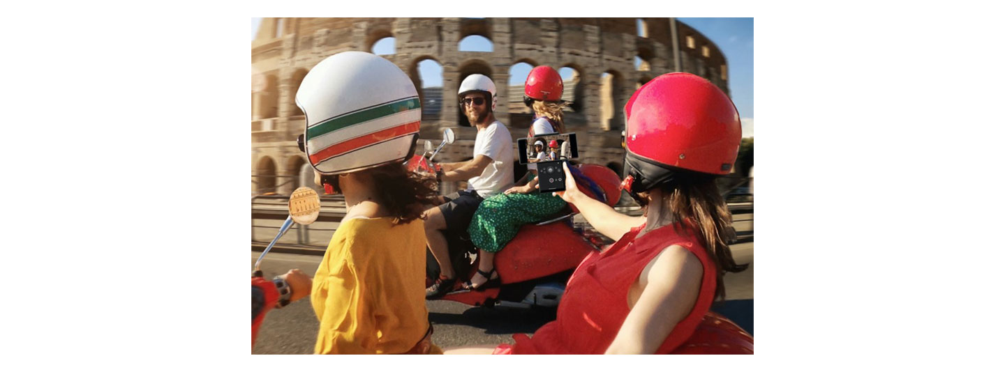 Four friends ride scooters in front of the Colosseum while a passenger uses LG WING’s unique camera capabilities to capture the action perfectly