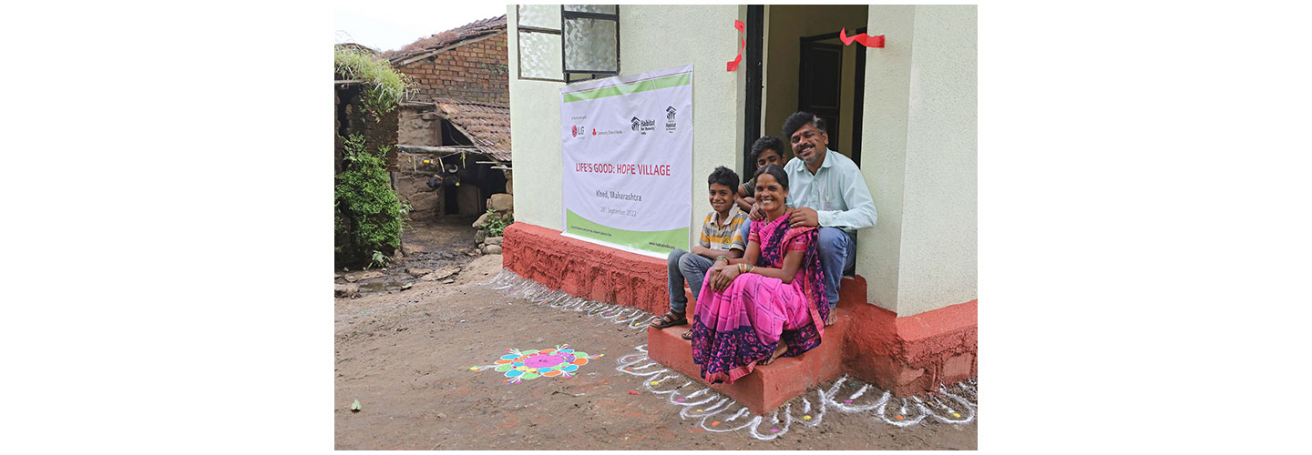 An Indian family posing together at the entrance of their house that was rebuilt through Life's Good: Hope Village project