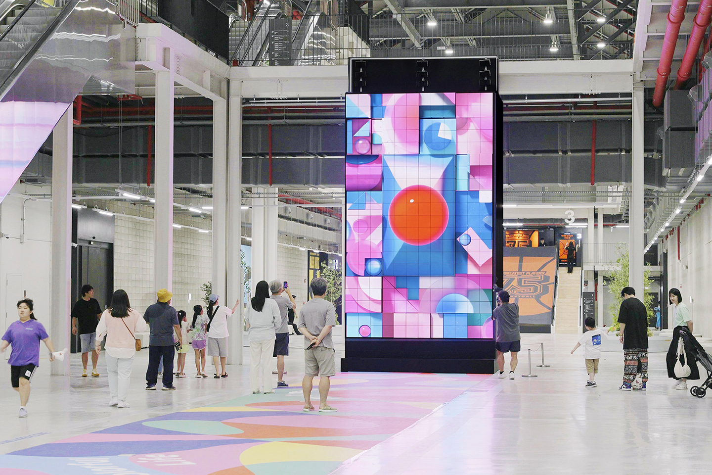 A picture of the kinetic LED signage displaying artwork with people walking by