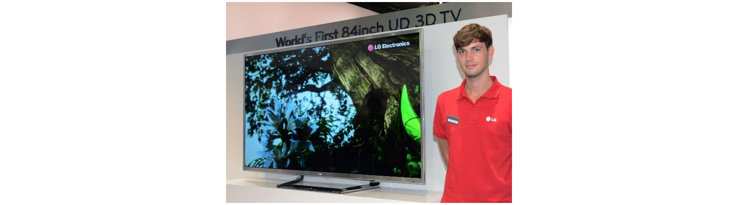 A male attendant stands next to the world's first LG 84-inch 4K 3D TV which is placed on a display stand.