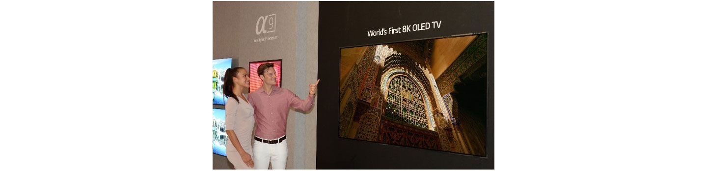 Another view of the World’s First 8K OLED TV with A9 Intelligent Processor display at IFA 2018, with a male and female model standing on the side pointing to the screen