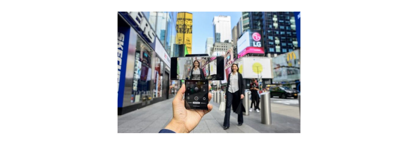 A person taking a picture of a woman walking toward the camera in Times Square with the help of LG WING's Swivel Mode capabilities