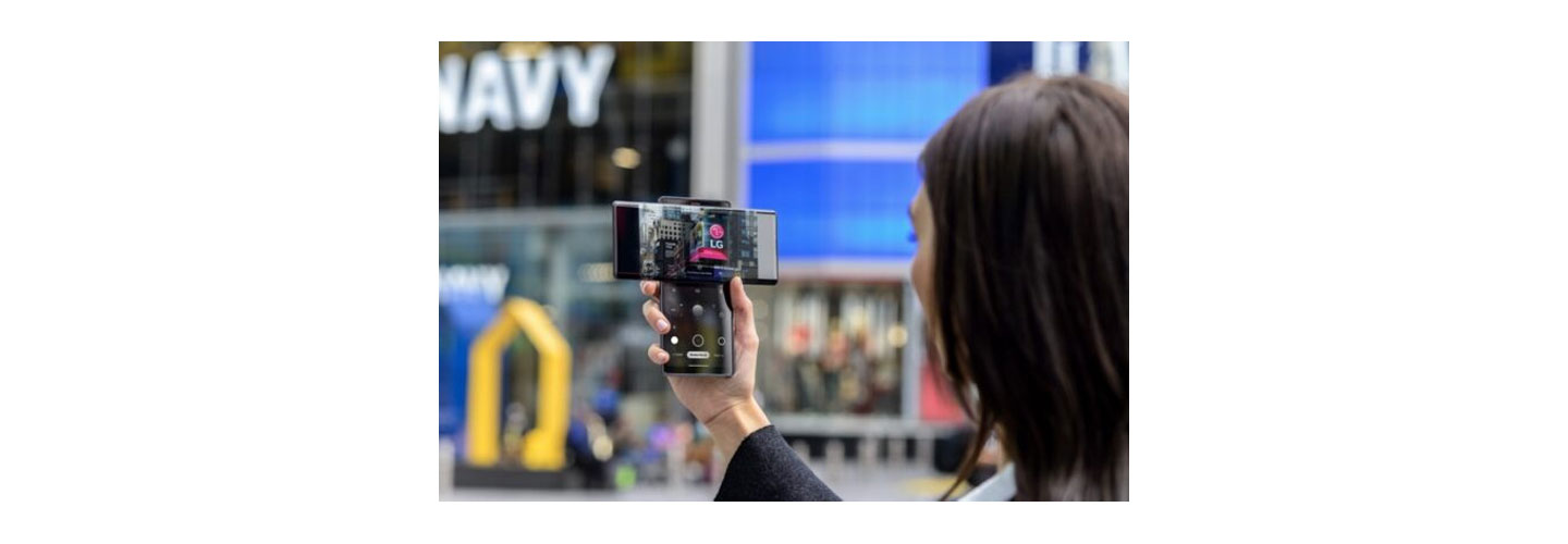 A woman taking a picture of the LG advertisement screen displayed in Times Square with LG WING in Swivel Mode
