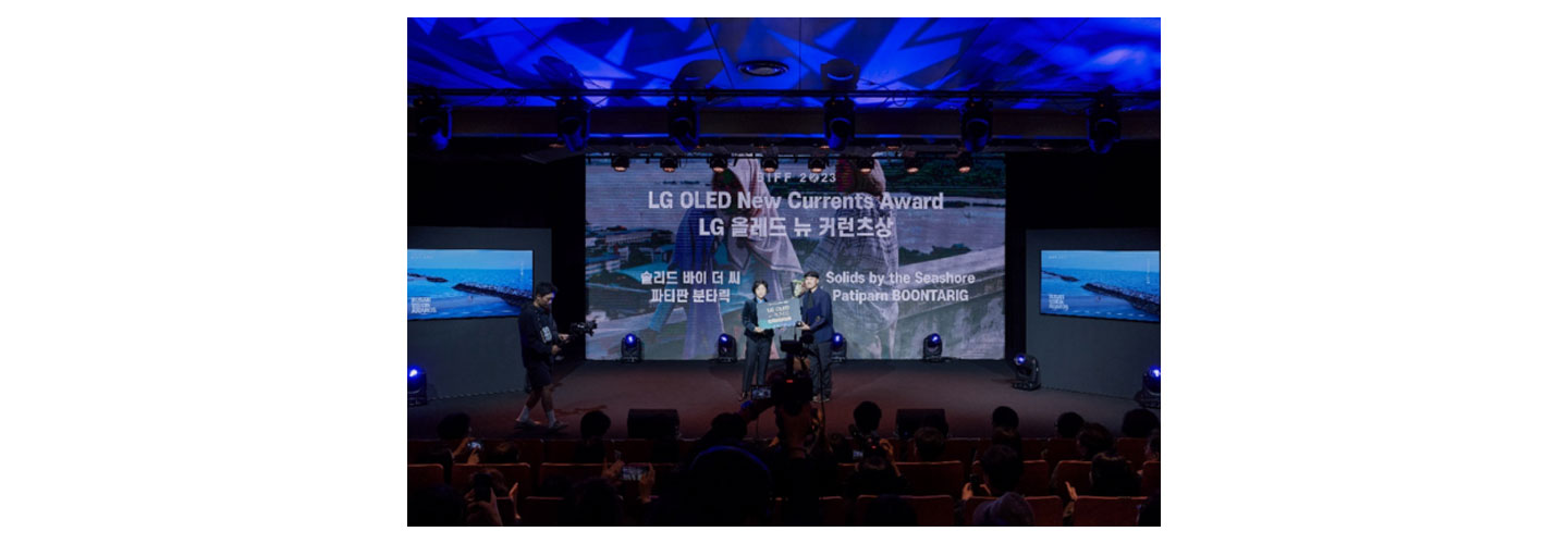 Two filmmakers receiving the LG OLED New Currents Award on the stage of the Busan International Film Festival