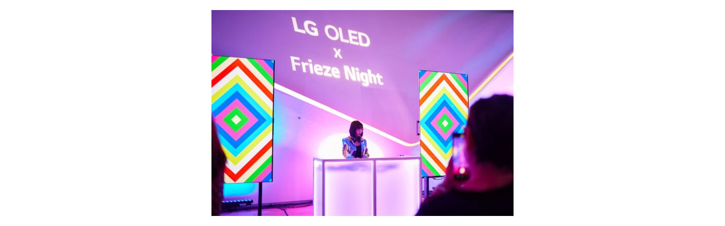 A woman in a colorful outfit DJing at LG OLED X Frieze Night