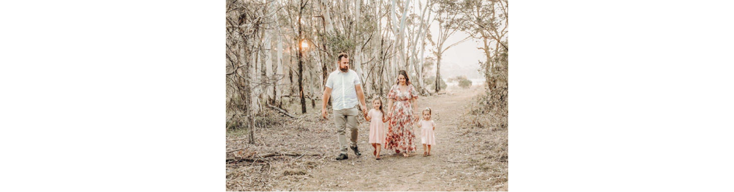  A family of four walking hand-in-hand through an Australian forest that has been ravaged by one of last year’s bush fires.