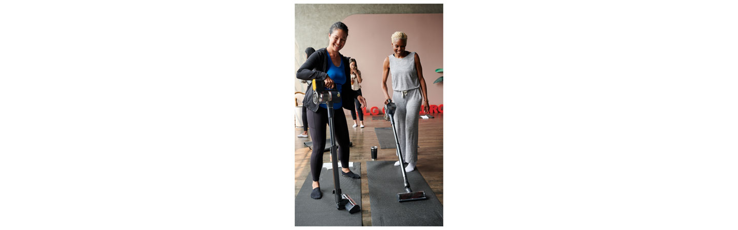 Two participants of the puppy yoga class using LG CordZero vacuum to clean up
