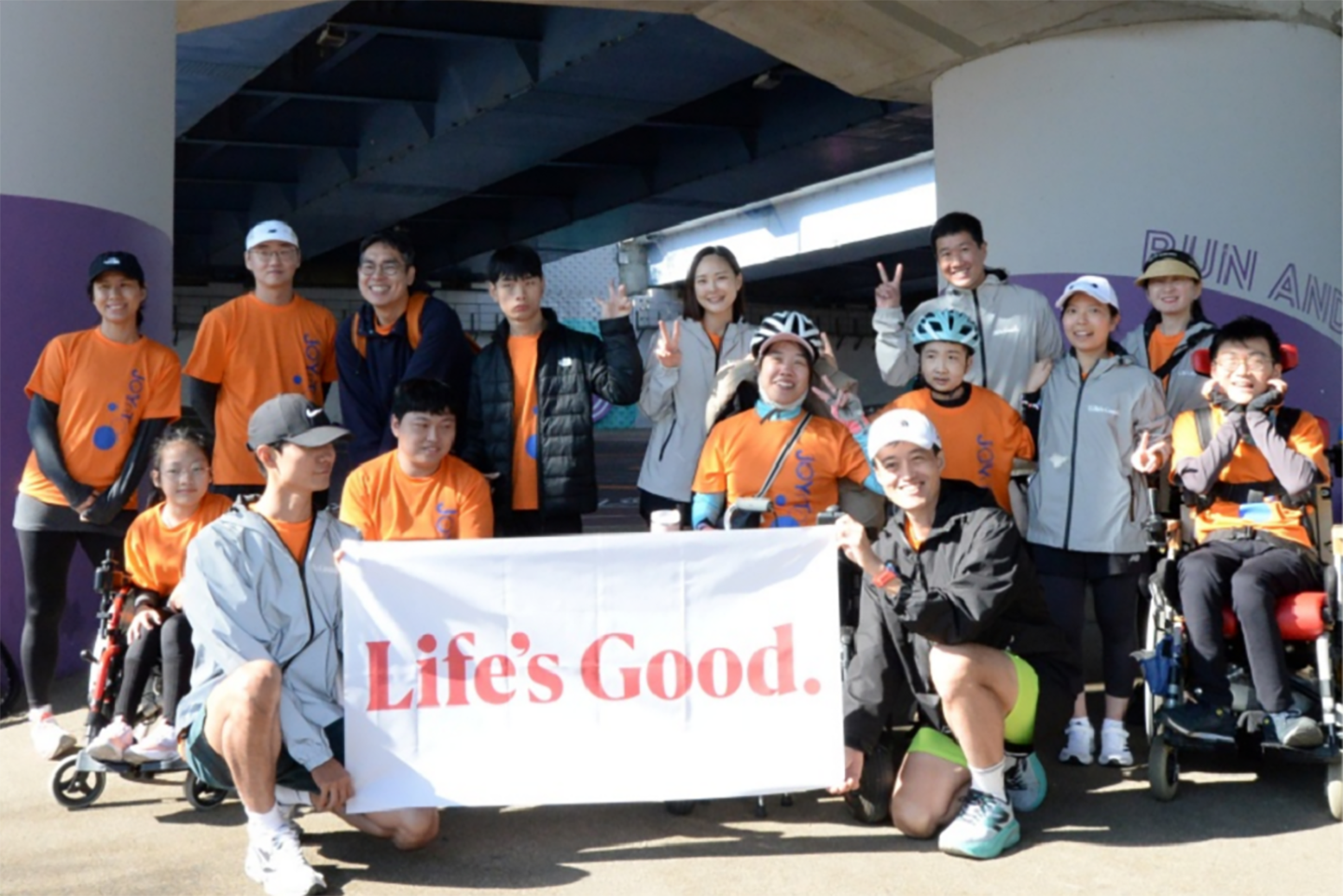 A photo of participants in the 2024 JTBC Seoul Marathon and LG employees smiling with the Life's Good banner
