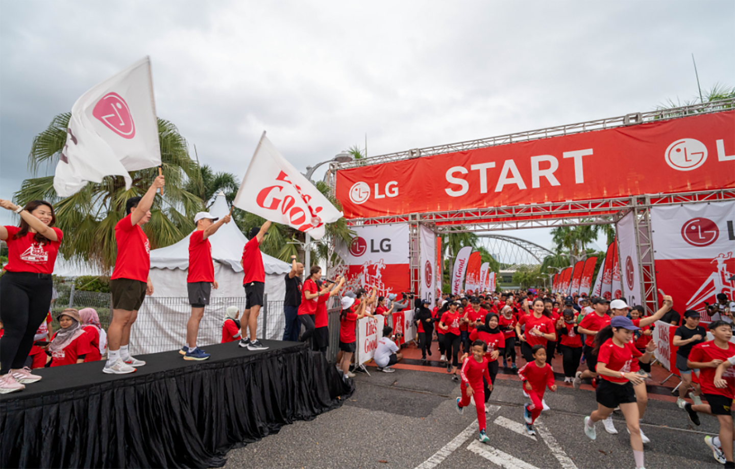 A photo of people running hard at the start line of the LG Marathon in Malaysia, with people waving Life's good flags on the sidelines