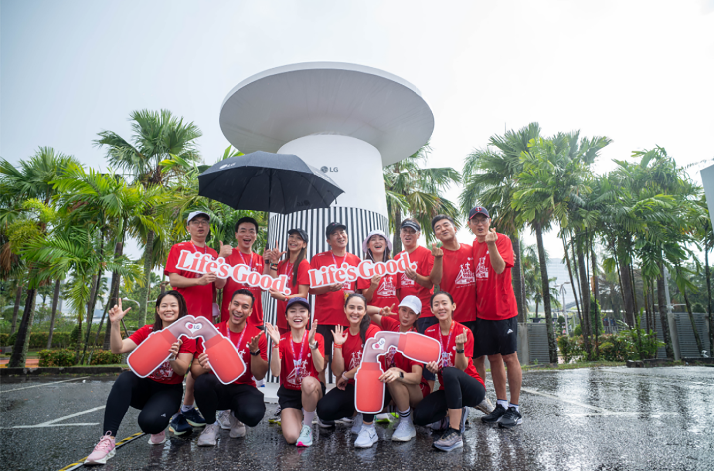 A photo of people smiling in front of a large outdoor LG product mockup