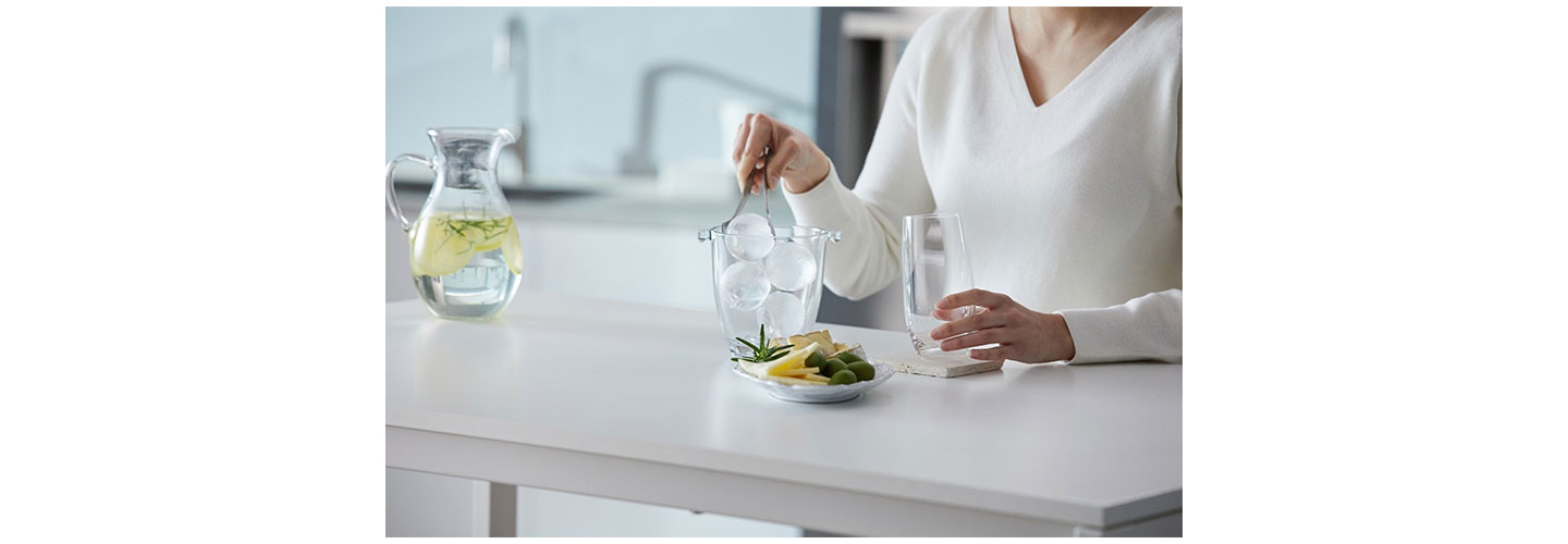 A woman using LG’s spherical Craft Ice balls while preparing a drink.