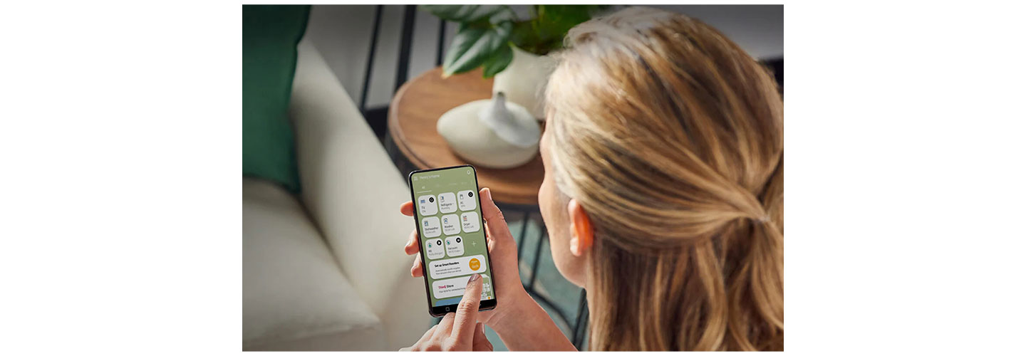 A woman using the LG ThinQ app to control her LG InstaView refrigerator.