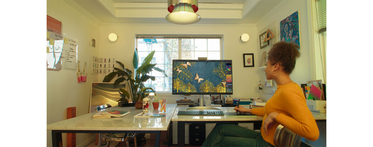 A woman is editing an image using LG UltraFine monitor and a mousepad