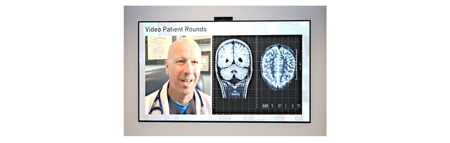An image of video patient round - A screen displaying a X-ray result and a doctor