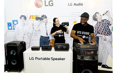 A man and woman both test LG’s speaker products at the BTS Studio Presented by LG.