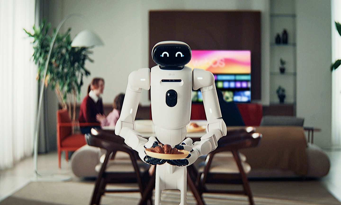 The LG CLOiDTM home robot holds out a croissant, with a family in a cozy living space in the background.