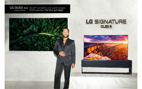 Singer John Legend posing in front of LG 97-inch G2 OLED evo TV and LG SIGNATURE OLED R TV at CEDIA Expo 2022