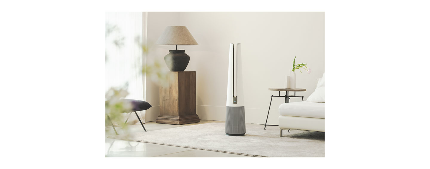 A front view of LG PuriCare AeroTower Beige air purifying fan in a bright room next to traditional interior decoration.
