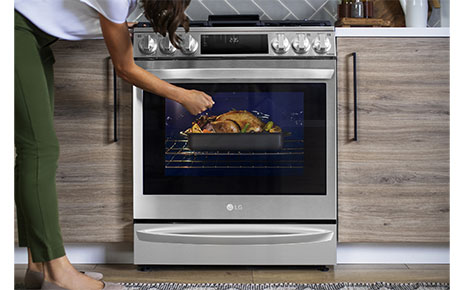 A woman is knocking on the glass window of the oven of InstaView® Range to see inside