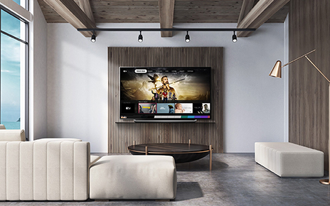 A view of an LG TV hanging on the wall of a wide modern living room as it displays the Apple TV app.