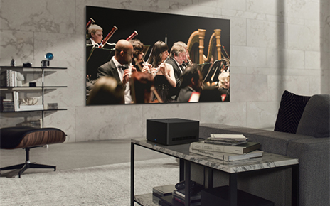 The newly revealed LG SIGNATURE OLED M3 TV mounted on the wall of a gray-themed living room as it displays an orchestra performance