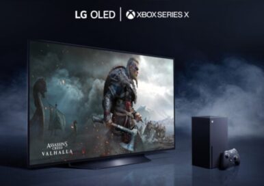 LG OLED TV placed in a dark room filled with mysterious smoke as it displays a battle scene from Assassin's Creed Valhalla, the latest video game available on LG official partner Microsoft’s Xbox Series X console which is seen to the right of the TV