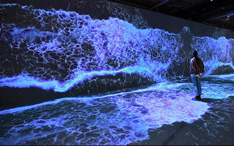 A visitor fully immersed in the white and blue waves being realistically reproduced through an art installation utilizing LG OLED displays