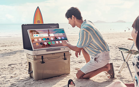 A couple using LG StanbyME Go on a sandy beach
