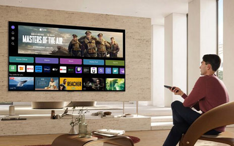 A man is using a TV remote to browse content on the webOS platform screen