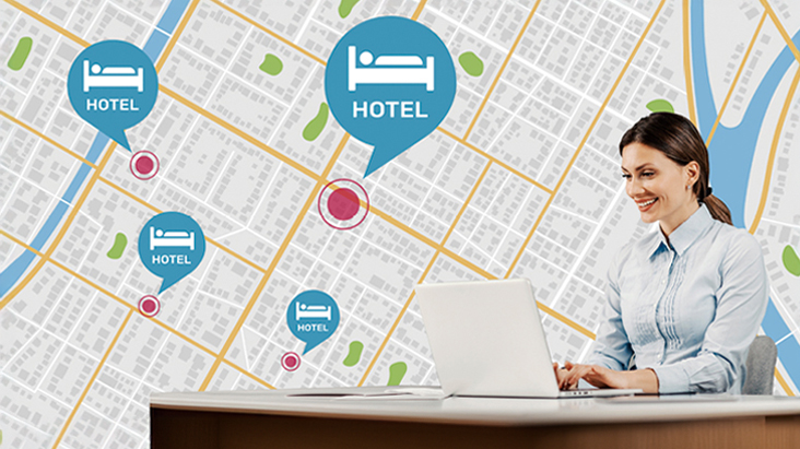 A woman sitting at the desk is using her PC to manage hotel TVs across different locations.