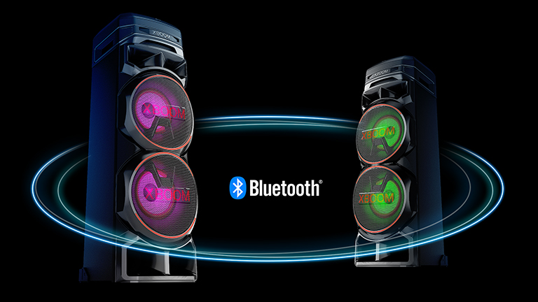 LG RNC9 Two RNC9s facing each other at diagonal angles against a black background with a Bluetooth logo in between. One has purple light on the woofer, and the other has green light.