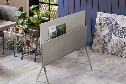 Posé seen from the back with nature magazines placed on the media shelf in a plant-themed living room.