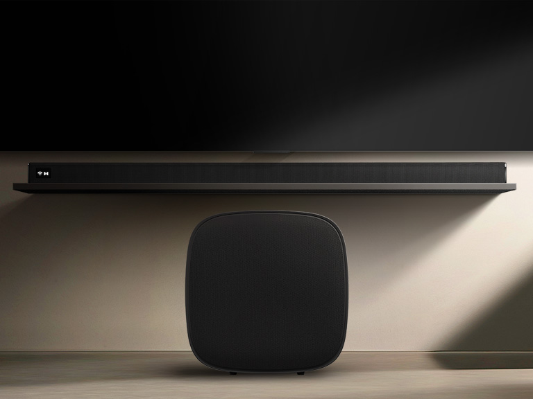 LG Sound Suite W7 woofer placed below a TV with a soundbar, showing easy wireless sound expansion for an immersive home stereo audio system