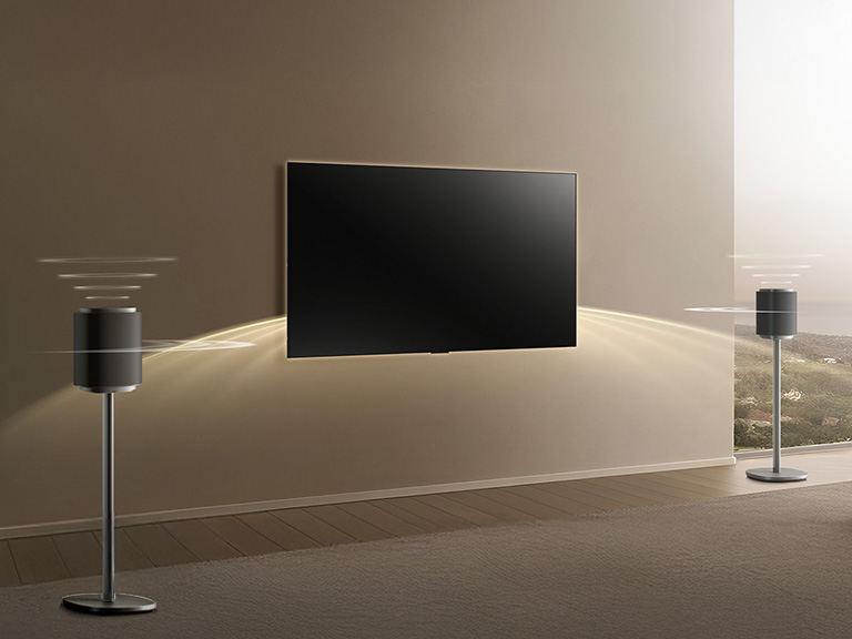 LG complete home theater system with Sound Suite speakers on both sides of the TV, emitting sound waves across the room for full Dolby Atmos