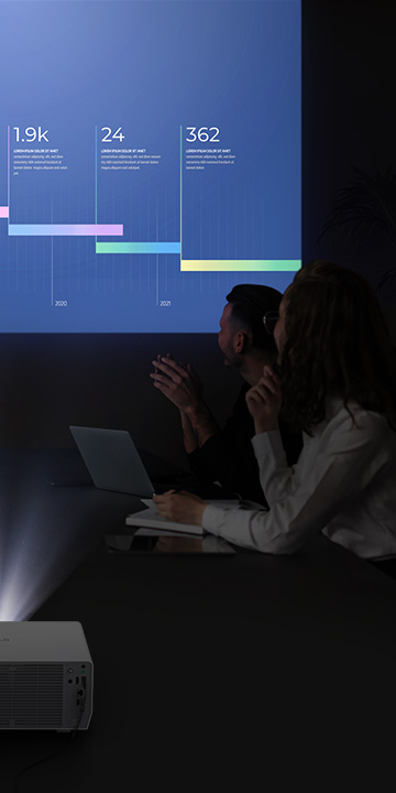 Five people are having a meeting in a dark room, viewing a vibrant display with the LG ProBeam projector.