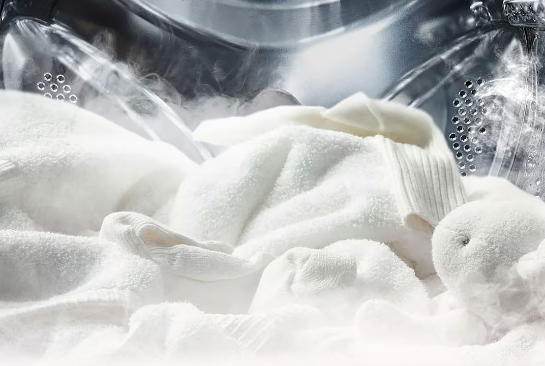 Close-up of soft white laundry with visible steam inside an LG drum illustrates steam technology for gentle fabric care and freshness.