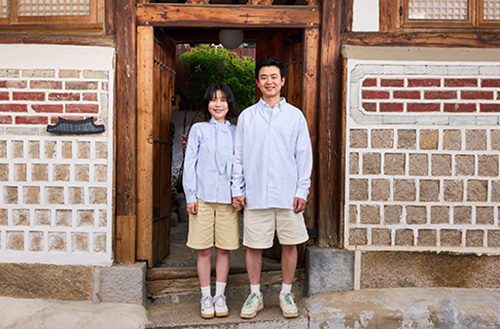 The hosts are standing in front of the Hanok Guesthouse.