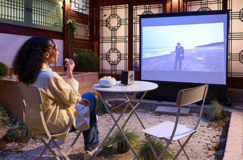 A guest watches a movie projected on a screen with CineBeam