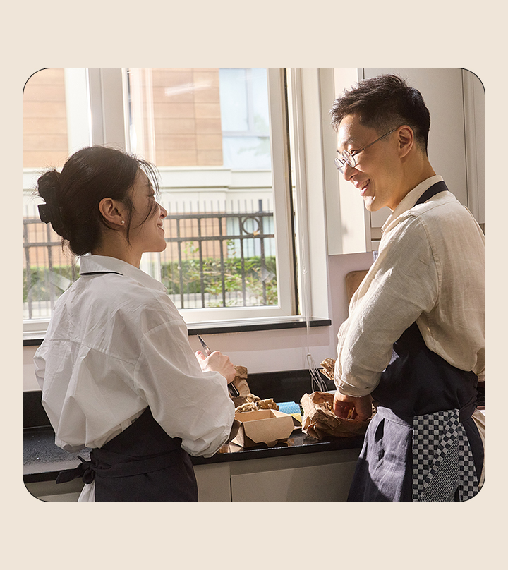 A man and a woman looking at each other while cooking in the kitchen.