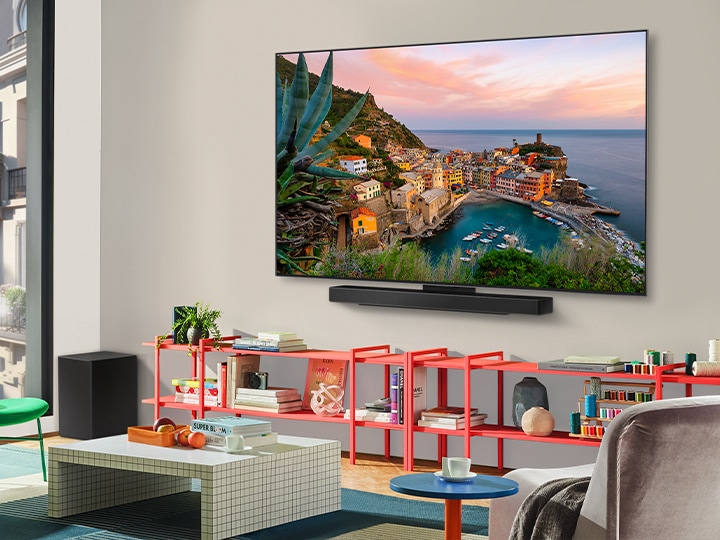 In a colorful living room is a wall-mounted LG OLED TV with Soundbar. The perspective is at an angle showing the ultra slim frame of the TV against the wall. 