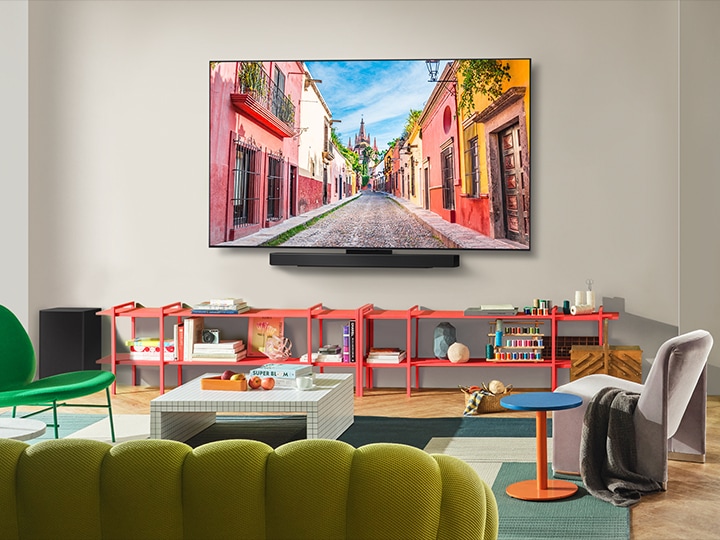 Front-facing view of the wall-mounted LG OLED TV with Soundbar in a colorful living room showcasing its Ultra Slim Design and how it blends perfectly in the space. 