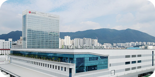 An exterior view of the LG Electronics Changwon Smart Park factory complex with mountains and a cityscape in the background