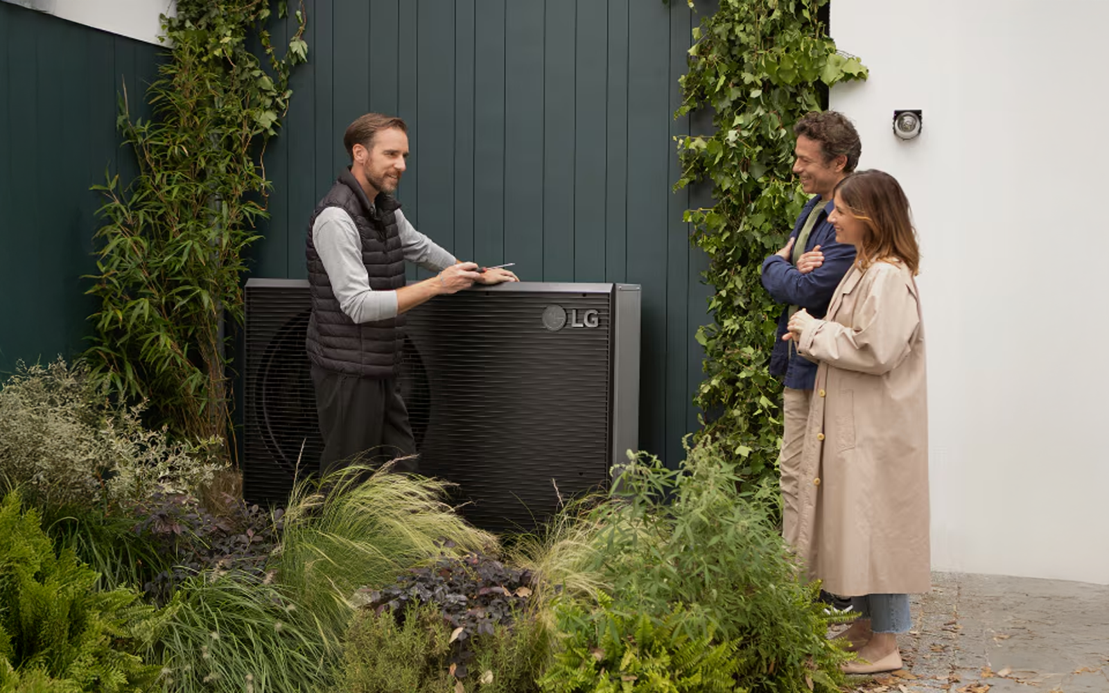A couple listening to a technician's explanation of an LG outdoor unit.