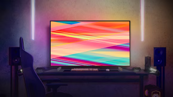 LG OLED C2 is in a warmly-lit room at night with sofas, lots of cushions, a lamp, a side table, and a plant